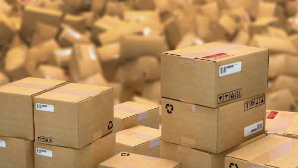 Neatly organised stack of cardboard boxes in front of a large disorganised heap of parels